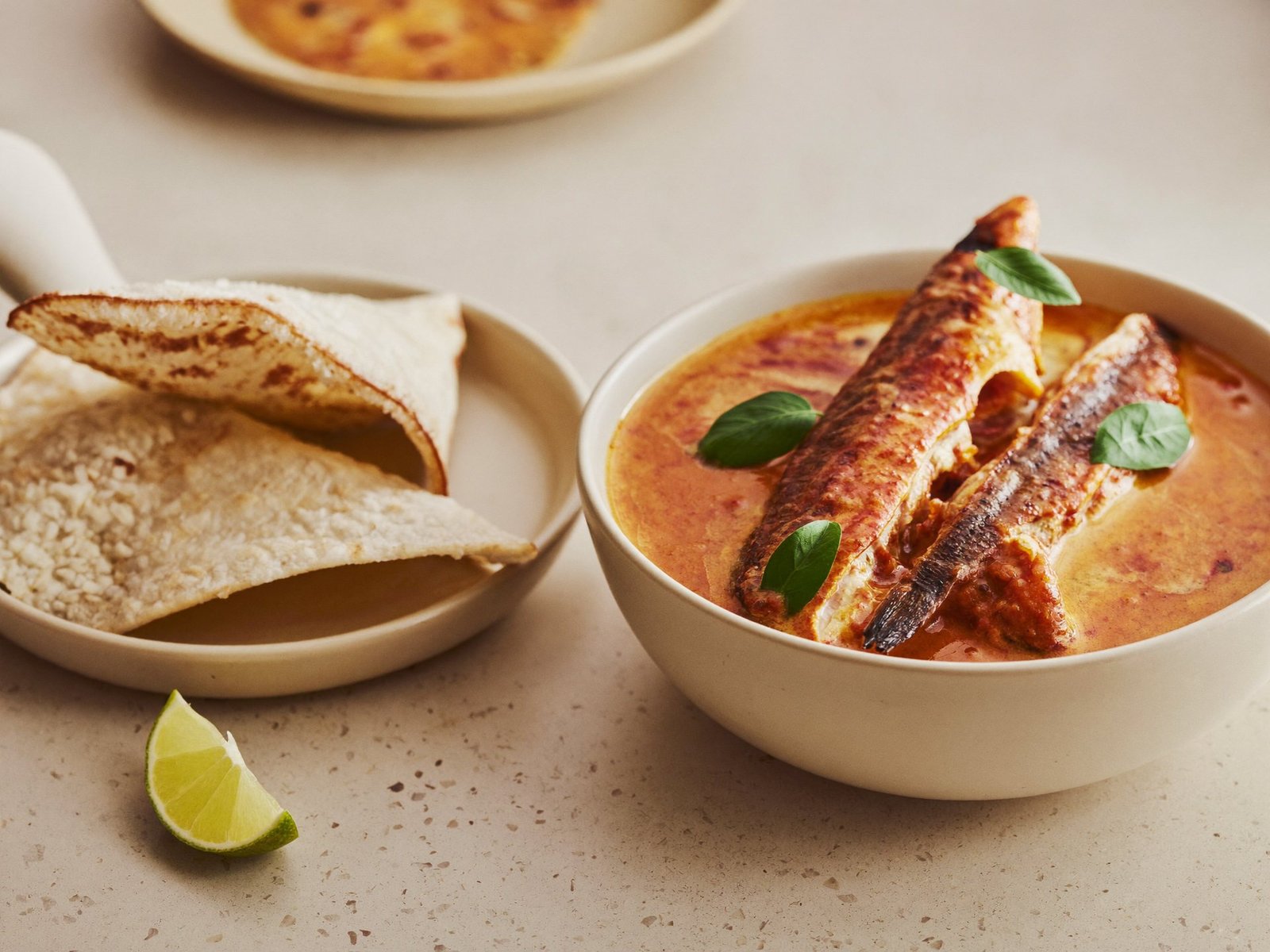 Kerala red fish curry in a bowl served with pathiri bread